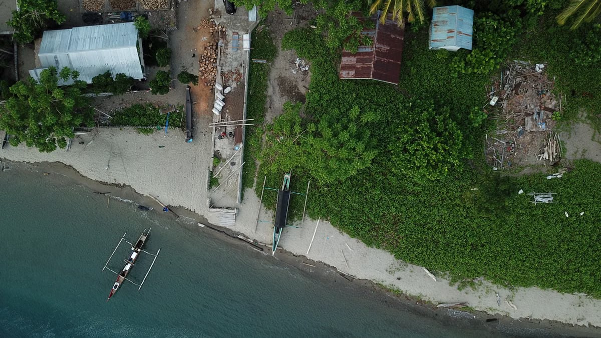 Drone shot capturing a coastal scene with boats and greenery in Una-Una, Indonesia.